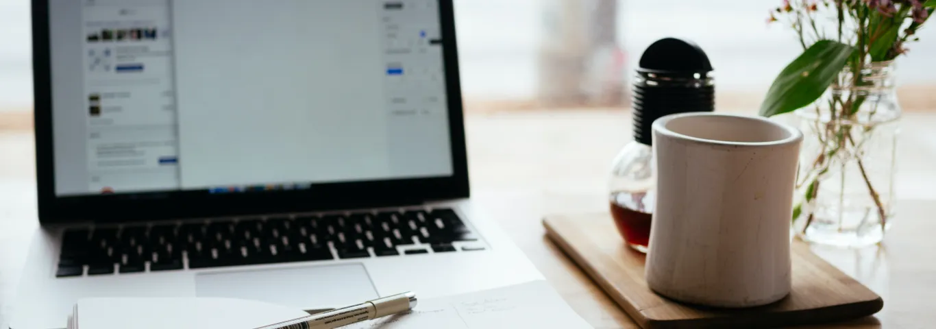 notebook laying open on a table with laptop on in the background
